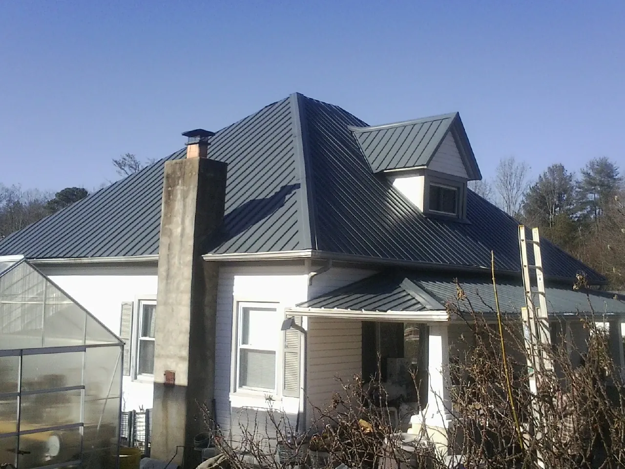 Dark blue standing seam metal roof on a white farmhouse with dormer — Slate & Tile Roof Repair by Roofing Brothers in Kaylor